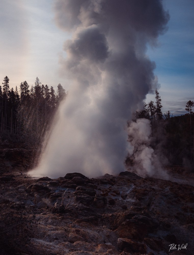 Steamboat Geyser erupts a minor eruption in front of the sun at Norris Geyser Basin in Yellowstone National Park.