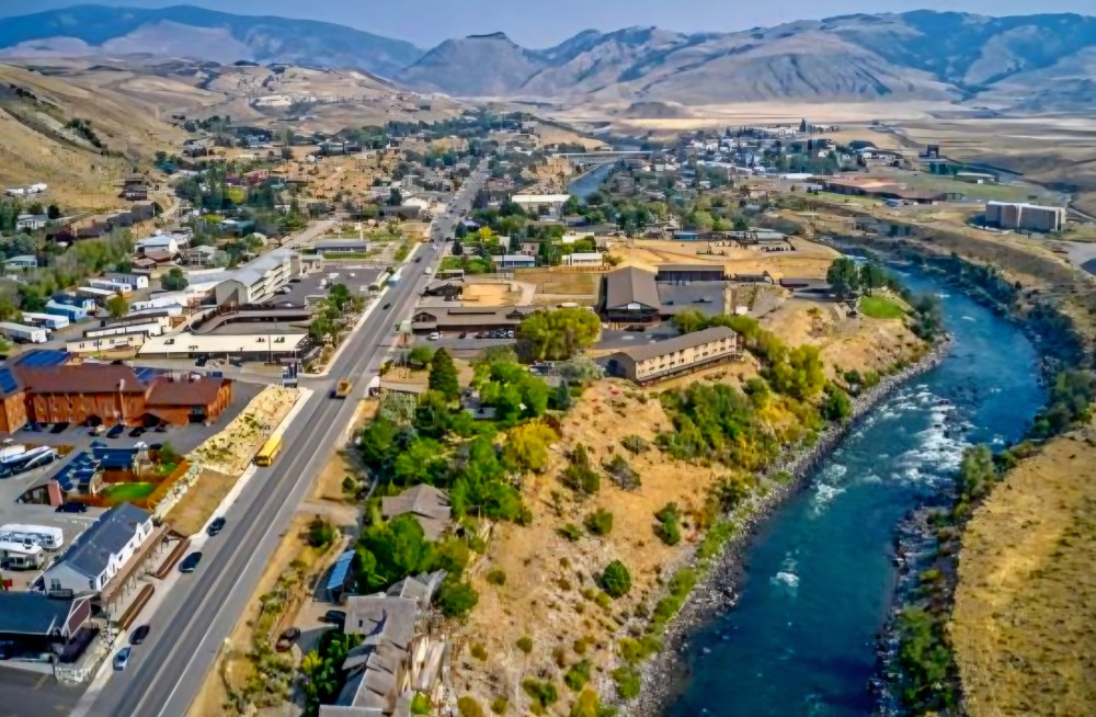 Aerial view of a riverside town with mountains in the background.